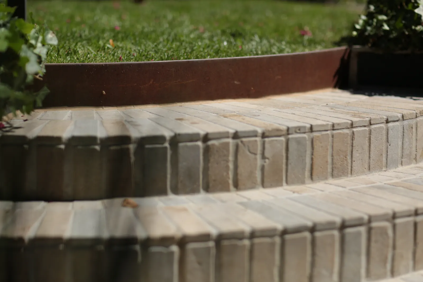 FormBoss Redcor steel edging retaining lawn above curved stone brick steps